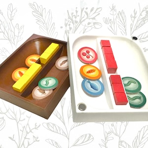 May include: Two wooden trays with compartments for a board game. One tray is brown with yellow, green, and red tokens. The other tray is white with red, green, and blue tokens.
