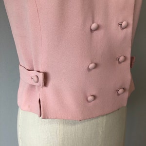 May include: A pink double-breasted blazer with a fitted silhouette and five buttons.