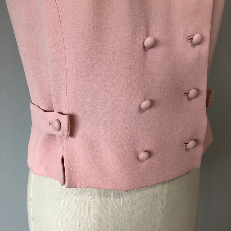 May include: A pink double-breasted blazer with a fitted silhouette and five buttons.