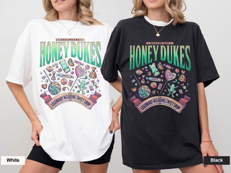 May include: White and black t-shirts with a colorful graphic design. The design features the text "Honeydukes" in green and a variety of candies and sweets. The text "Legendary Wizarding Sweet Shop" is also included.