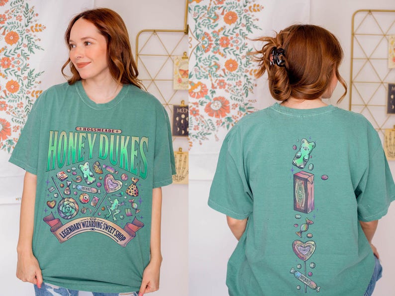 May include: A teal t-shirt with a graphic of sweets and the text "Honeydukes Legendary Wizarding Sweet Shop." The back of the shirt features a gummy bear, candy box, and other sweets. The shirt is a comfortable, oversized fit.