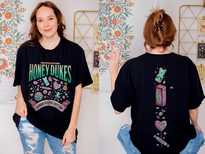 May include: Black t-shirt with the text "HONEY DUKES" in green and blue, featuring a colorful illustration of candies and sweets. The back of the shirt has a vertical design with a gummy bear, a box, and various candies.