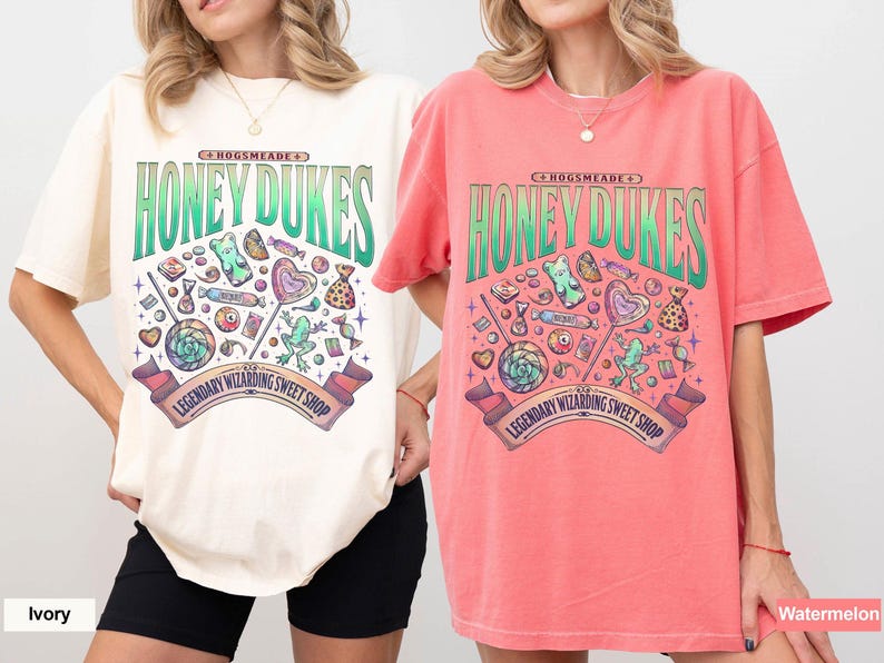May include: Ivory and watermelon-colored t-shirts with a Honeydukes graphic. The design features the text "Honeydukes" in green, along with various candies and the text "Legendary Wizarding Sweet Shop".
