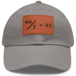 Może przedstawiać: Szara czapka bejsbolówka z brązowym skórzanym naszywką, na której widnieje napis "99/2 = 92".
