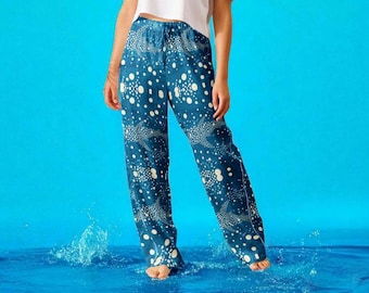 May include: Blue patterned pants with a white dot and sea creature design. The pants have a drawstring waist and a relaxed fit. The model is standing in water, creating a splash.