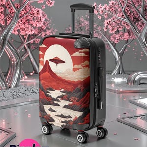 May include: Black and red rolling suitcase with a landscape design featuring a UFO, mountains, and a river. The suitcase has a retractable handle and four wheels. The Ripplez logo is visible in the bottom left corner.