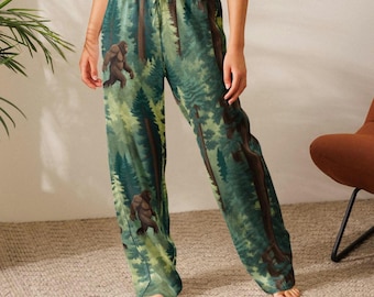 May include: Green pajama pants with a forest and Bigfoot design. The pants feature a repeating pattern of trees and a brown Bigfoot figure. The pants have a drawstring waist and a relaxed fit.