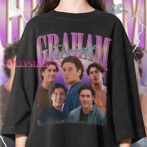 May include: A black short-sleeve t-shirt featuring a graphic print of a person in five different poses. The text GRAHAM is printed in large purple letters above the name Garrett in teal script. The background has a purple gradient and lightning.