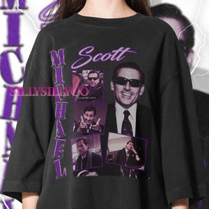 May include: Black t-shirt featuring a collage of images of Michael Scott, with the name "Michael Scott" in purple script. The shirt includes the text "It's Britney, Bitch" and the seller's logo.