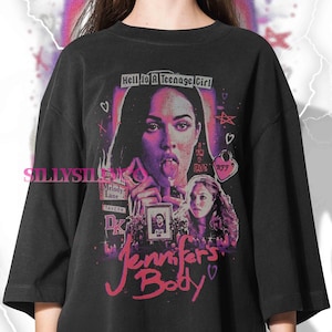 May include: Black oversized t-shirt featuring a graphic design from the movie "Jennifer's Body." The design includes a portrait of a woman with her tongue out, the text "Hell Is A Teenage Girl," and the movie title in pink script.