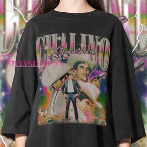 Puede incluir: Camiseta negra de gran tama&ntilde;o con un gr&aacute;fico vintage de Chalino S&aacute;nchez. El dise&ntilde;o incluye m&uacute;ltiples im&aacute;genes del cantante, su nombre y un fondo retro colorido. La camiseta tiene un corte holgado.