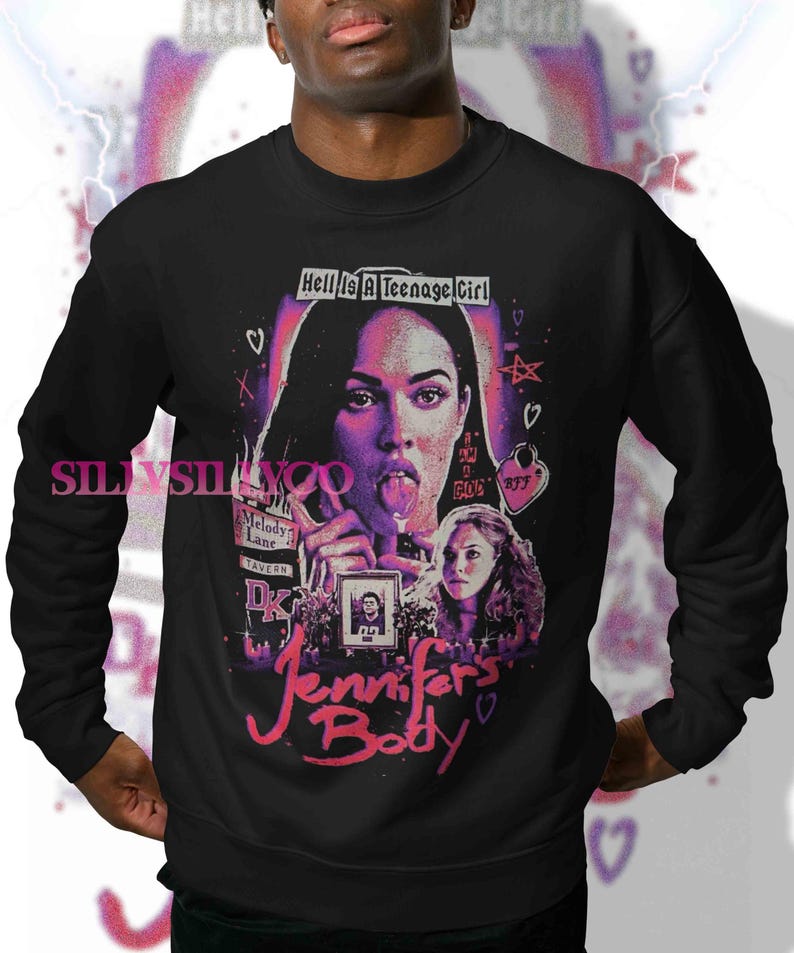 May include: Black sweatshirt featuring a graphic from the movie "Jennifer's Body." The design includes a portrait of a woman with her tongue out, the text "Hell Is A Teenage Girl," and the movie title in pink script.