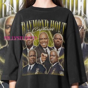 May include: Black t-shirt featuring a graphic of Raymond Holt, with the text "RAYMOND HOLT Captain" in gold lettering. The design includes multiple images of the character with lightning bolt accents.