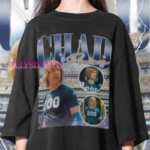 May include: Black t-shirt featuring a graphic of a man with the name "CHAD POWERS" in a retro style. The shirt includes three circular images of the man wearing a blue shirt with the number "200". The shirt has a vintage aesthetic.