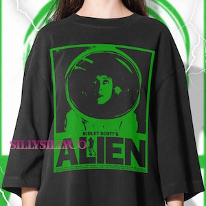 Pu&ograve; includere: T-shirt nero con grafica verde del film Alien di Ridley Scott. La grafica presenta un ritratto di una donna con un casco spaziale e il titolo del film. La maglietta ha una vestibilit&agrave; ampia e maniche corte.