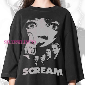 May include: Black t-shirt with a grayscale graphic from the film "Scream". The design includes a close-up of a face with wide eyes, and the word "SCREAM" in large, bold letters. The shirt also features images of the movie's cast.