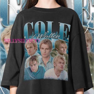 以下が含まれることがあります： 黒いTシャツ。男性のグラフィックと「COLE Walter」の文字が青色のグラデーションで描かれています。グラフィックには男性の複数の画像が含まれています。このシャツはヴィンテージ感があります。