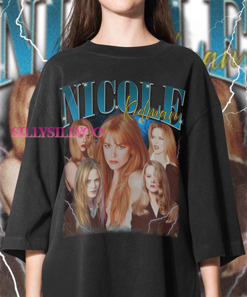 Puede incluir: Camiseta negra de gran tama&ntilde;o con un dise&ntilde;o gr&aacute;fico de Nicole Kidman. El dise&ntilde;o presenta el texto "NICOLE Kidman" en azul y amarillo, junto con m&uacute;ltiples im&aacute;genes de la actriz. El dise&ntilde;o tiene una est&eacute;tica vintage con acentos de rayos.