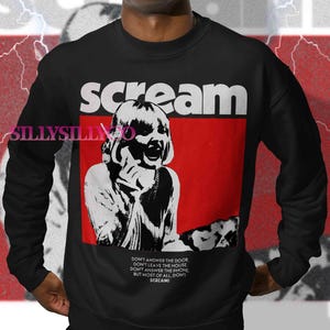 May include: Black sweatshirt with the word "scream" in white block letters above a red rectangle. Inside the rectangle is a black and white image of a person. Below the image is text that reads "DON'T ANSWER THE DOOR...SCREAM!"