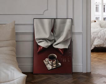 Puede incluir: Una impresión de arte mural enmarcada que muestra un pantalón gris claro de pierna ancha y zapatos rojos brillantes de punta fina sobre una taza de espresso plateada con platillo y café negro, sobre un fondo rojo oscuro profundo.