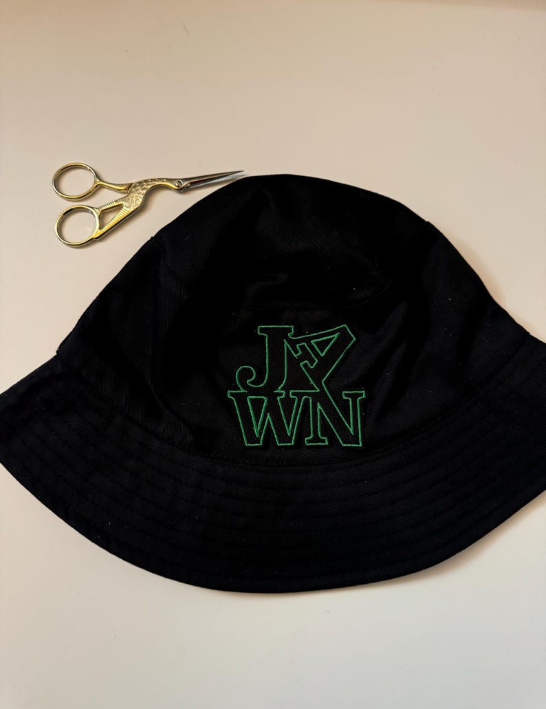 May include: Black bucket hat with a green embroidered logo that says "J.Y. WIN".