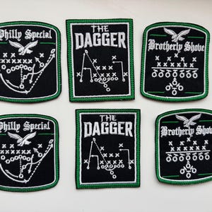 May include: Six embroidered patches featuring black fabric with green borders. Two patches display Philly Special with an eagle and play diagram, two show The Dagger with a play diagram, and two show Brotherly Shove with an eagle and play diagram.