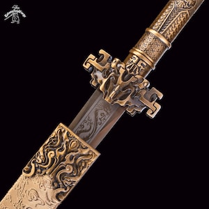 May include: Close-up of a decorative sword with intricate gold-colored metalwork. The blade features a detailed dragon engraving. The hilt and guard are adorned with ornate patterns. The sword is set against a dark background.