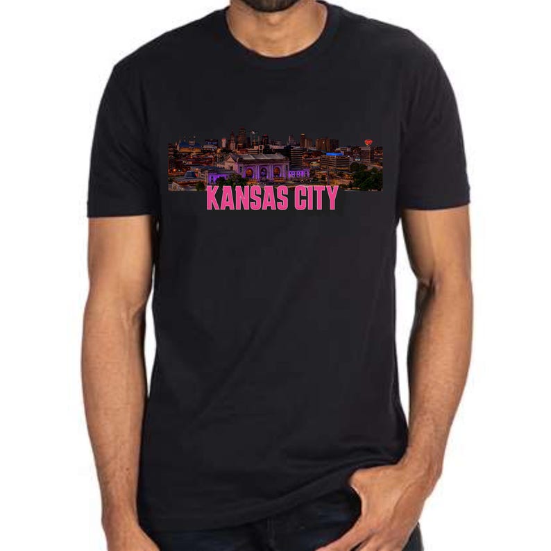 May include: Black t-shirt with a skyline of Kansas City in purple and pink with the text "KANSAS CITY" in pink.