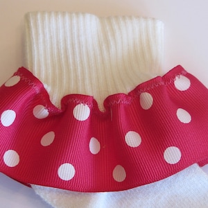 May include: White sock with a pink and white polka dot ruffle around the top.