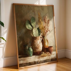 以下が含まれることがあります： サボテン、ドライフラワー、さまざまな陶器の花瓶を描いた、額装された静物画。 このアートワークは、アースカラーの暖色系の色使いで、壁に立てかけられています。 フレームは明るい茶色です。