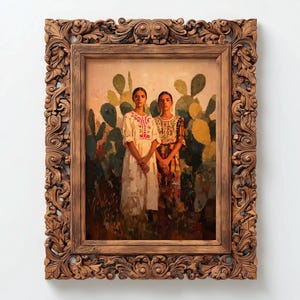 May include: A framed painting featuring two women in traditional dresses standing in front of cacti. The ornate wooden frame surrounds the artwork, which has a warm color palette. The women's dresses have colorful embroidery.