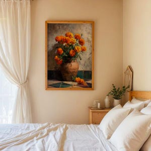 May include: A framed art print featuring a still life of orange marigold flowers in a brown ceramic vase. The artwork is set against a neutral background with a hint of green and blue tile. The frame is made of light-colored wood.