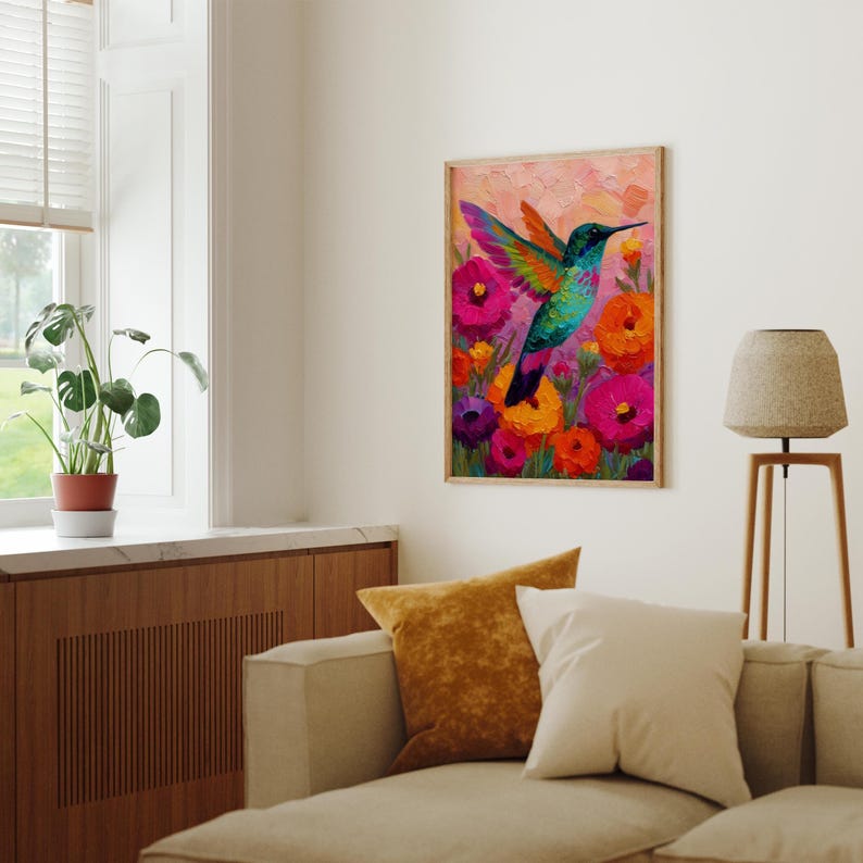May include: A framed painting depicting a hummingbird in flight, with vivid colours. The bird features a turquoise body and multi-coloured wings, set against a backdrop of bright pink, orange, and purple flowers. The artwork is displayed in a living room.
