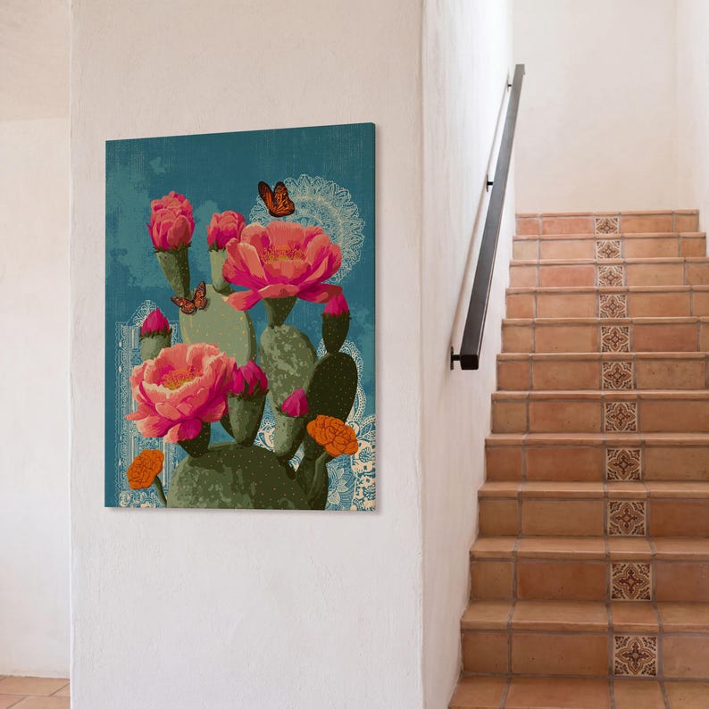 Pode incluir: Uma impress&atilde;o em tela com um cacto estilizado com grandes flores rosa e detalhes em laranja sobre um fundo azul turquesa. Borboletas e um padr&atilde;o de renda branca adicionam detalhes. A obra de arte &eacute; exibida em uma parede branca.