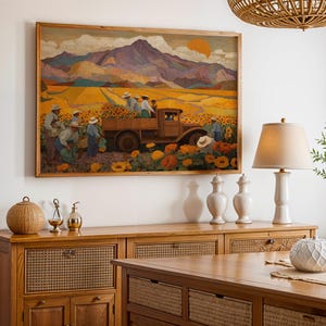 May include: A framed painting depicts a field of sunflowers with workers harvesting them. A vintage truck is loaded with sunflowers. The background features mountains and a setting sun. The painting is in a wooden frame and hangs above a wooden cabinet.