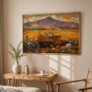 May include: A framed artwork depicts a harvest scene with a vintage truck loaded with sunflowers. The painting features a field of sunflowers, workers, and a mountain range under a setting sun. The artwork is displayed above a wooden table with a vase and a coffee cup.
