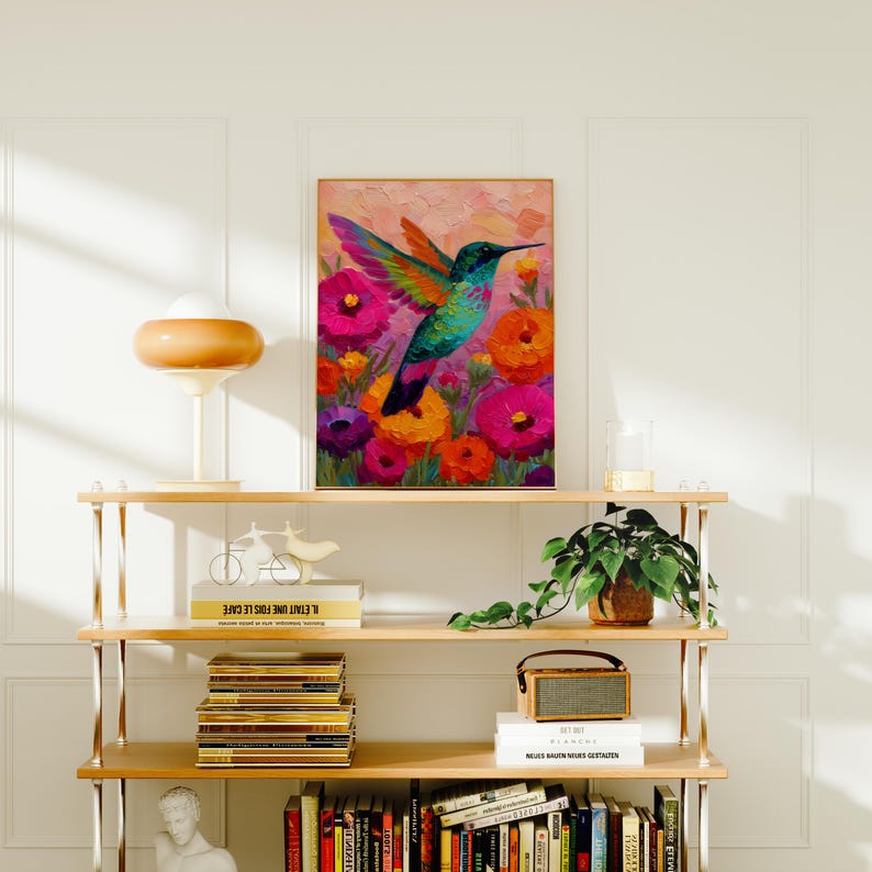 May include: A framed art print depicting a hummingbird in flight, set against a backdrop of colourful flowers. The bird has turquoise feathers and a long beak. The flowers are shades of pink, orange, and purple.