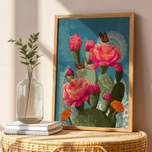 May include: A framed art print featuring a vibrant illustration of a cactus with large pink flowers and orange accents against a teal background. Butterflies and decorative patterns add detail to the botanical artwork.