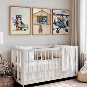 Set of 3 digital nursery prints featuring an aviator bear, vintage biplanes, and cozy airplane hangar scenes. Perfect for an aviator nursery, airplane nursery, baby boy travel room, pilot baby room, vintage nursery decor, and adventure-themed baby rooms. Ideal wall art for baby showers, nursery wall displays, and cozy baby room corners. Soft neutral colors with a classic vintage aviation theme.