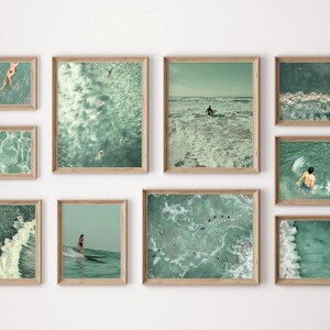 May include: A collage of nine framed photographs of ocean waves in various shades of blue and green. The photos are arranged in a grid pattern on a white wall.