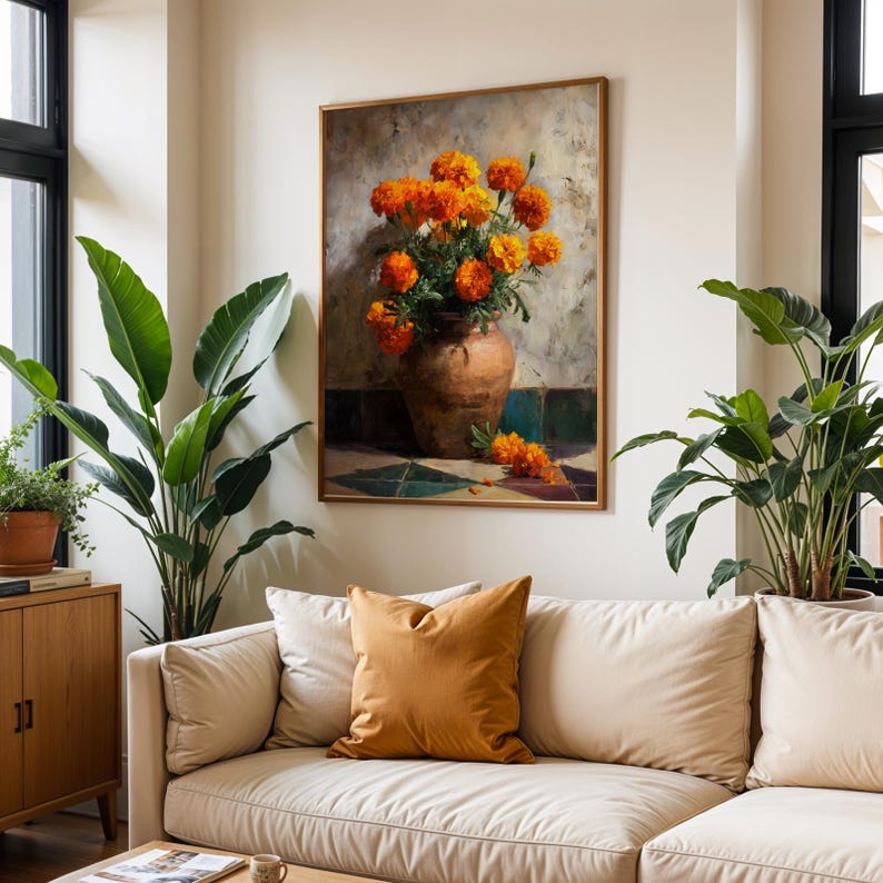 May include: A framed painting of orange marigold flowers in a brown vase. The artwork hangs above a cream-colored sofa with an orange pillow. Green plants flank the sofa, adding a touch of nature to the room.
