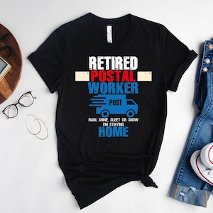 May include: Black t-shirt with the text "Retired Postal Worker" in white, red, and blue. A blue postal truck graphic is below the text, with the phrase "Rain, shine, sleet or snow I'm staying home."