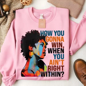 May include: Pink sweatshirt with a colorful illustration of a woman with an afro and the text "How you gonna win, when you ain't right within?"