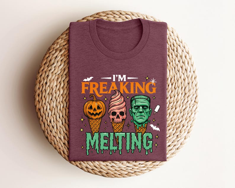 K&ouml;nnte beinhalten: Burgunderfarbenes T-Shirt mit einem Halloween-Motiv. Das Design zeigt drei Eist&uuml;ten mit gruseligen Gesichtern: einen K&uuml;rbis, einen Totenkopf und Frankensteins Monster. Der Text lautet "I'M FREAKING MELTING".