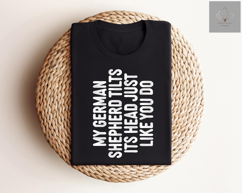 May include: Black t-shirt with white text that reads "My German Shepherd Tilts Its Head Just Like You Do."
