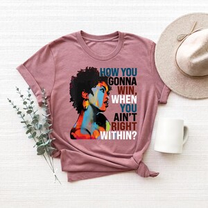 May include: A mauve t-shirt with a colorful illustration of a woman with an afro and the text "How you gonna win, when you ain't right within?"