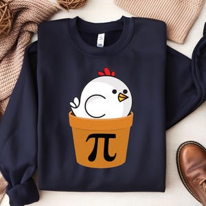 May include: A navy blue sweatshirt with a white chicken in a pot with the symbol pi printed on it.