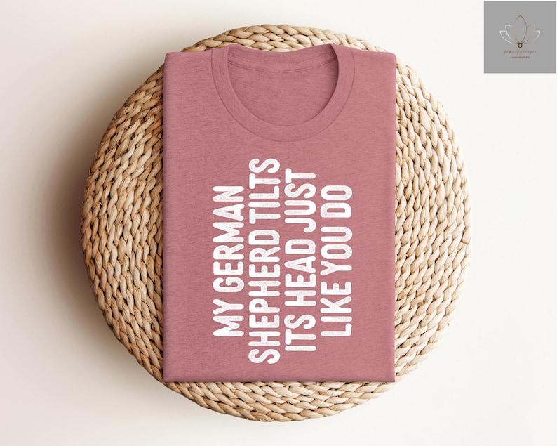 May include: A pink t-shirt with the text "My German Shepherd Tilts Its Head Just Like You Do" printed in white.