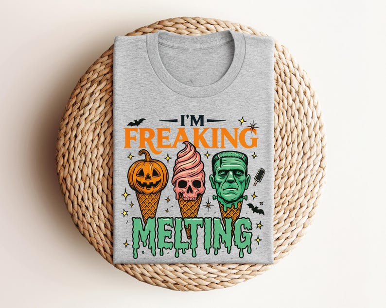 K&ouml;nnte beinhalten: Ein graues T-Shirt mit einem Halloween-Motiv. Das Design zeigt einen K&uuml;rbis, einen Totenkopf und Frankensteins Monster als Eist&uuml;ten, mit dem Text "I'M FREAKING MELTING".