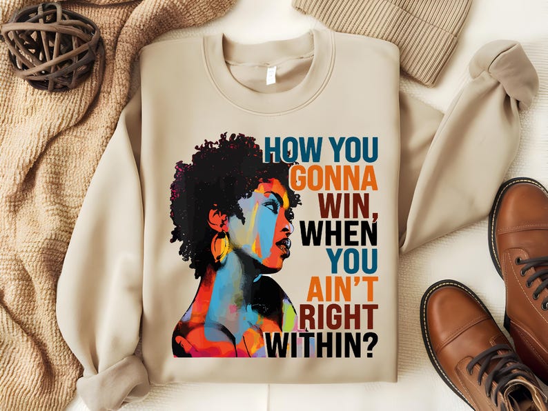 May include: Beige sweatshirt with a colorful illustration of a woman with an afro and the text "HOW YOU GONNA WIN, WHEN YOU AIN'T RIGHT WITHIN?"